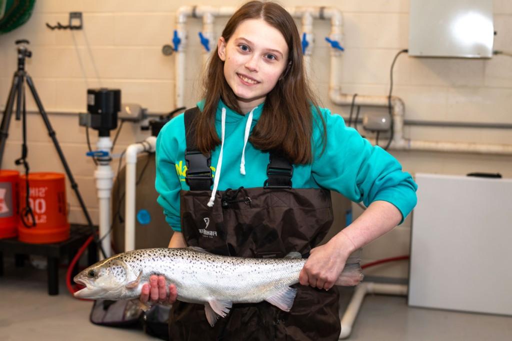 在海洋科学中心，一名穿着工作服的学生举着一条鱼