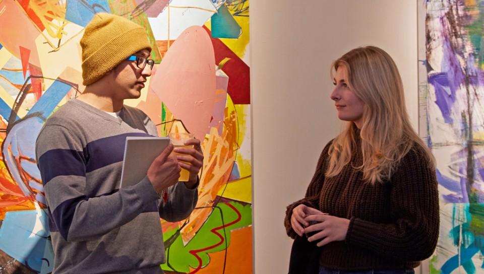 纽恩大学的学生们在纽恩大学波特兰美术馆的两幅大型彩色画作前交谈