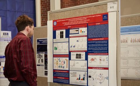 A student reads a research poster at the first annual symposium on biomedical research and engineering